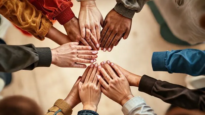 A photorealistic image depicting diverse hands clasped together in a circle, symbolizing community and support. The hands are of different ages and backgrounds, conveying unity and strength. Soft, warm lighting, sharp focus on the hands, depth of field blurring a gentle background. 8K, professional photography. A photorealistic image depicting diverse hands clasped together in a circle, symbolizing community and support. The hands are of different ages and backgrounds, conveying unity and strength. Soft, warm lighting, sharp focus on the hands, depth of field blurring a gentle background. 8K, professional photography.